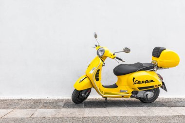 Santorini, Yunanistan - 9 Ocak 2019: Restoranın ahşap duvarına park edilmiş klasik sarı Vespa. İkonik İtalyan tasarımı scooter. Scooter eski Akdeniz şehrinin boş caddesinde duruyor.