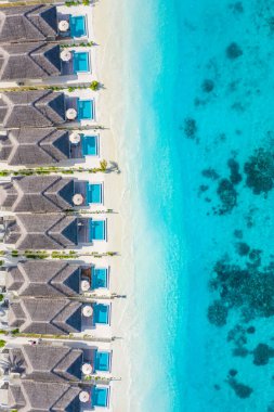 Aerial view of Maldives island, luxury water villas resort and wooden pier. Beautiful sky and ocean lagoon beach background. Summer vacation holiday and travel concept. Paradise aerial landscape pano clipart