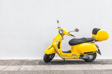 Santorini, Yunanistan - 9 Ocak 2019: Restoranın ahşap duvarına park edilmiş klasik sarı Vespa. İkonik İtalyan tasarımı scooter. Scooter eski Akdeniz şehrinin boş caddesinde duruyor.