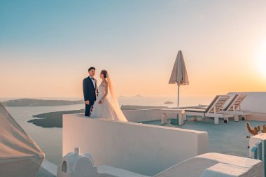 10.05.2019 - Sanorini, Yunanistan: Santorini, Yunanistan 'ın en romantik adasında genç çift balayı. Gün batımında düğün manzarası, yumuşak renklerde güzel bir çift. Aşk, balayı geçmişi