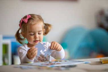 Küçük kız evde bulmacayla oynuyor.