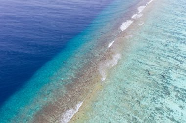 Mercan sahilinde dalgalar, güzel doğal kıyı, yaz mevsiminde kıyı arkaplanı. Tropik doğa düzeni, deniz okyanusu yüzeyi, üst hava manzarası. Dalgalı mavi gölgeler