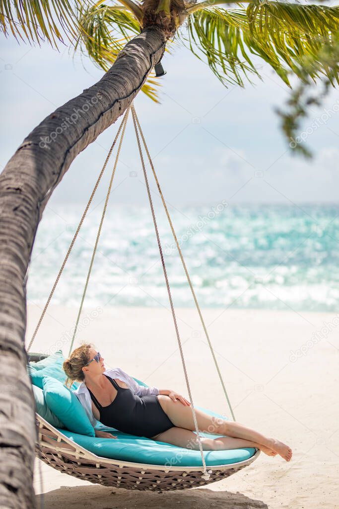 beautiful woman sitting on hammock on the beach