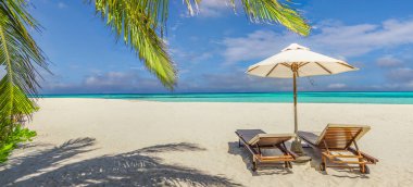 İki ahşap şezlong ve şemsiyenin el değmemiş tropik bir plajda yatay görüntüsü.