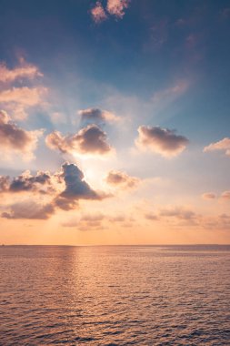Sakin turkuaz su üzerinde tropik günbatımı, pastel bulutlu gökyüzü..