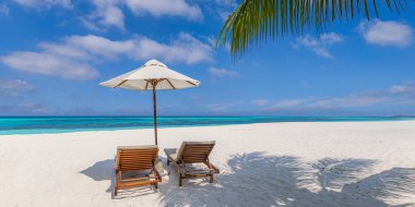 İki ahşap şezlong ve şemsiye el değmemiş bir tropik plajda..