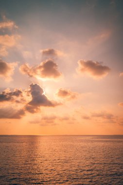 Sakin turkuaz su üzerinde tropik günbatımı, pastel bulutlu gökyüzü..