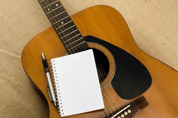 Blank paper with pen on old acoustic guitar — Stock Photo, Image