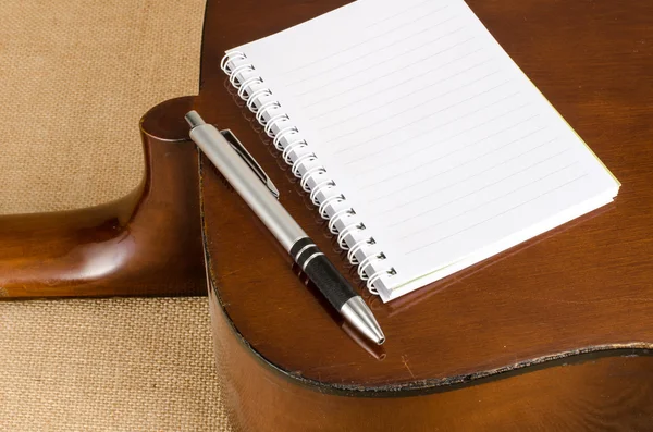 Blank paper with pen on old acoustic guitar — Stock Photo, Image