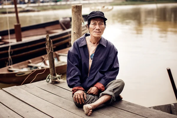 Oude man op een pier op rivier, vietnam. — Stockfoto