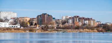 Şehir manzarası. Çok katlı yeni binaların inşa edildiği kıyılardaki donmuş nehirden panoramik görüntüler.