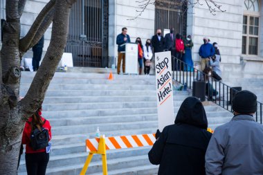 Portland Maine 'deki beyazların üstünlüğünü protesto etmek için Asyalıları destekleyen pankartlar tutan insanlar.