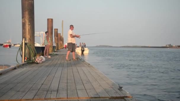 Mann mit Angelrute auf dem Deck in der Nähe des Ozeans. lizenzfreies Stockvideo