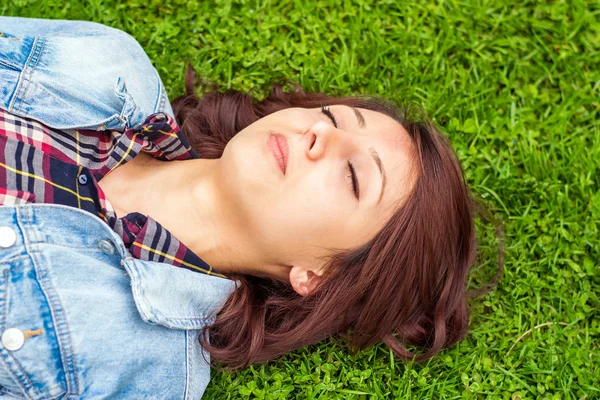Mladá žena ležící v trávě — Stock fotografie