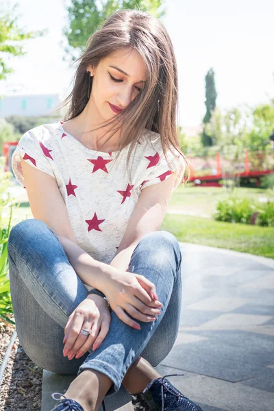 Hermosa morena sentada en un banco en el parque — Foto de Stock