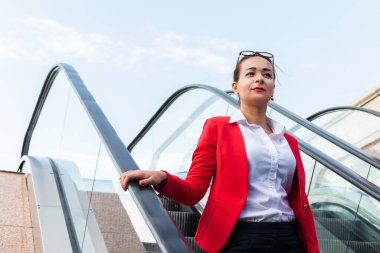 Başarılı iş kadını yürüyen merdivenden aşağı iniyor.