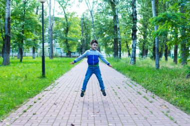 Eşofmanlı küçük bir çocuk parka atlıyor..