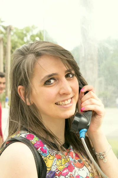 Chica cerca de una cabina telefónica — Foto de Stock