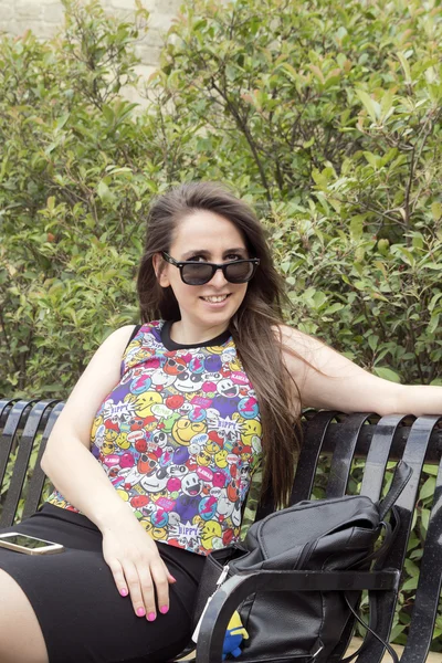 Das Mädchen auf der Bank mit Sonnenbrille — Stockfoto