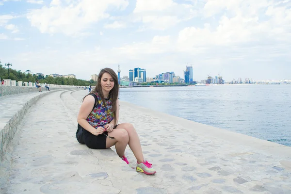 The girl sits on the waterfront — Stock Photo, Image