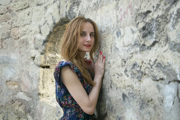 Chica joven cerca de un muro de piedra — Foto de Stock