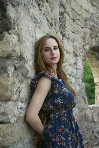 Jong meisje in de buurt van een stenen muur — Stockfoto