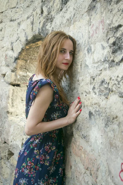 Chica joven cerca de un muro de piedra — Foto de Stock