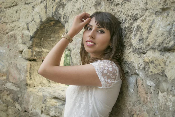 Chica joven cerca de un muro de piedra — Foto de Stock