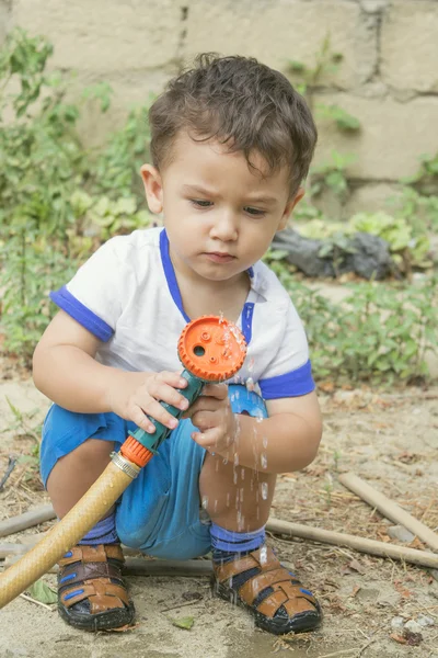 Niño jugando con manguera de jardín —  Fotos de Stock