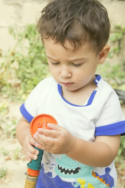 Chlapec hrát s zahradní hadice — Stock fotografie