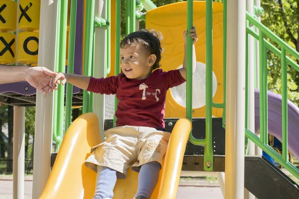 Der Junge auf dem Spielplatz geht diese Rutsche hinunter — Stockfoto