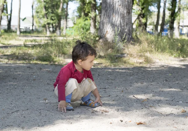 Boy is squatting outdoors — Stock Photo, Image