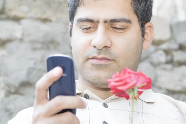 Сельский житель с розой и мобильным телефоном — стоковое фото