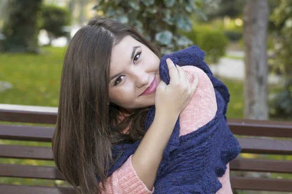 Brünettes Mädchen sitzt im Herbst auf einer Bank — Stockfoto