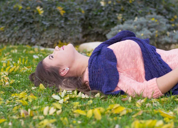 Junge Frau liegt im Herbst im Gras — Stockfoto