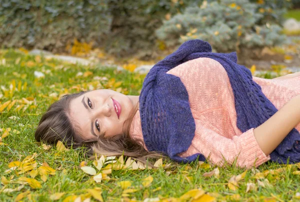 年轻女子在秋天躺在草地上 — 图库照片