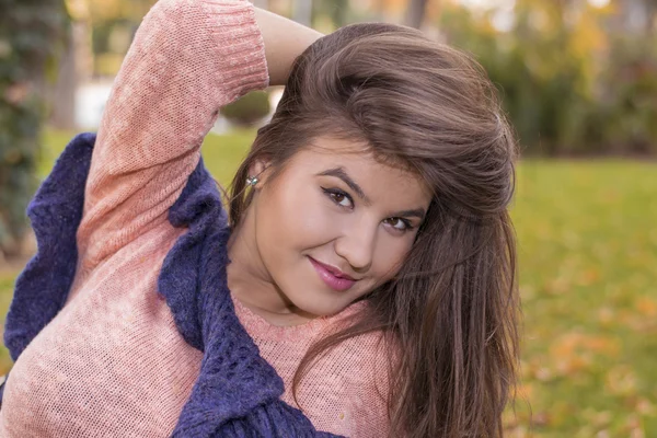 Brünettes Mädchen sitzt im Herbst auf dem Gras — Stockfoto