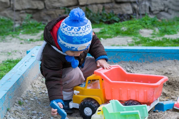 Мальчик в песочнице играет с машиной — стоковое фото