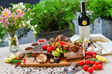 Restoranda şarap ve ahşap bir tahtada servis edilen ızgara et ve sebzelerden oluşan geniş bir çeşitlilik.