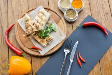 Shawarma, baharatlı bir masada tahta bir tahtanın üzerinde ikiye bölündü.