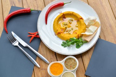 Masada kırmızı biber ve beyaz tabakta humus.