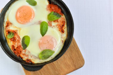 Ahşap bir arka planda çırpılmış yumurta kızartma tavasında pişmiş.