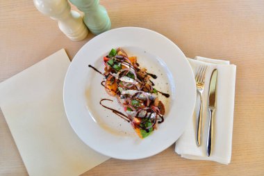 Ringa balıklı siyah ekmek, domates ve soğanlı bir tabak, üst görünüm.