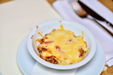 Masadaki beyaz tabakta peynirli lazanya.