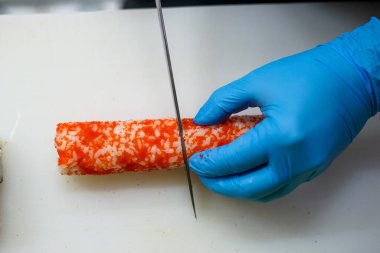 Suşi, gri arka planda beyaz bir tabakta havyar içinde yuvarlanır.