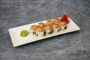 Suşi havyarla birlikte pirinç içinde, gri bir zemin üzerinde beyaz bir tabakta yemek dekoru ile yuvarlanıyor.