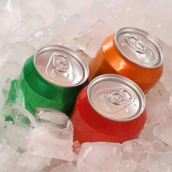 Cola and lemonade beverages in cans on ice — Stock Photo, Image