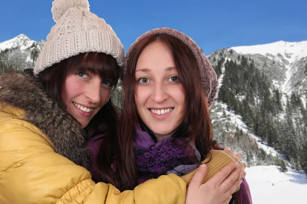 Due donne sorridenti si abbracciano in montagna — Foto Stock