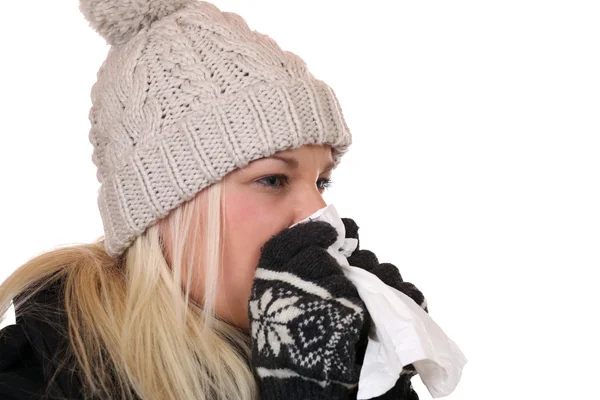 Young woman with a cold and flu virus sneezing into a tissue is — Stock Photo, Image