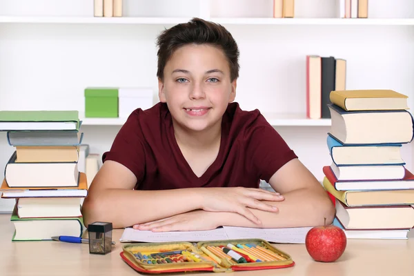 Feliz chico sonriente haciendo deberes en la escuela — Foto de Stock